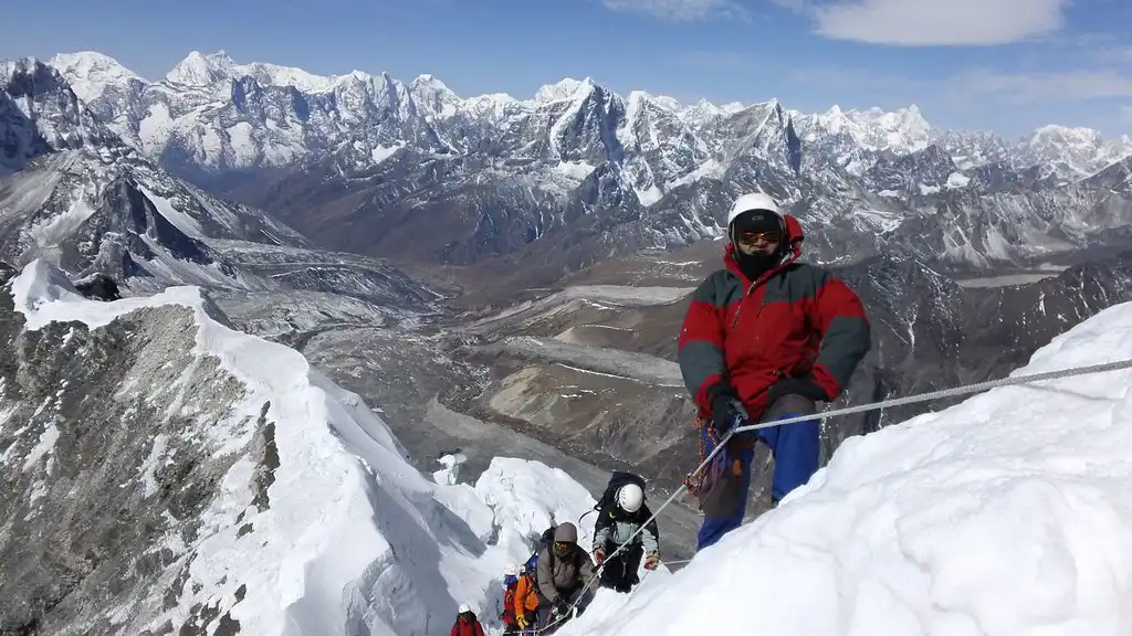 Climbers making their way up the snowy ridge of Island Peak, with vast Himalayan mountain ranges in the background.