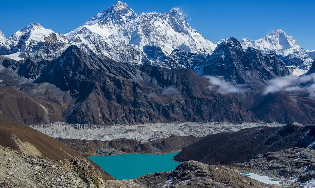 Panoramic view of Gokyo Lakes and surrounding Himalayan peaks as seen from Renjo La, with a vivid turquoise lake nestled among rugged mountains.