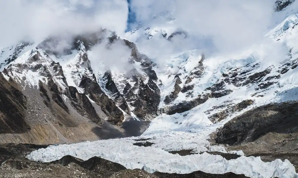 Dramatic view of the Khumbu Icefall with rugged peaks and swirling clouds in the Himalayas.