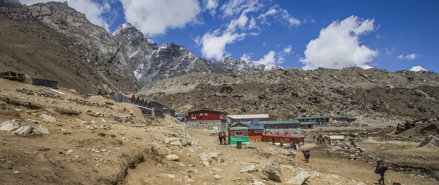 Lobuche Village nestled in the rocky, mountainous terrain of the Khumbu region, with trekkers walking through the settlement.