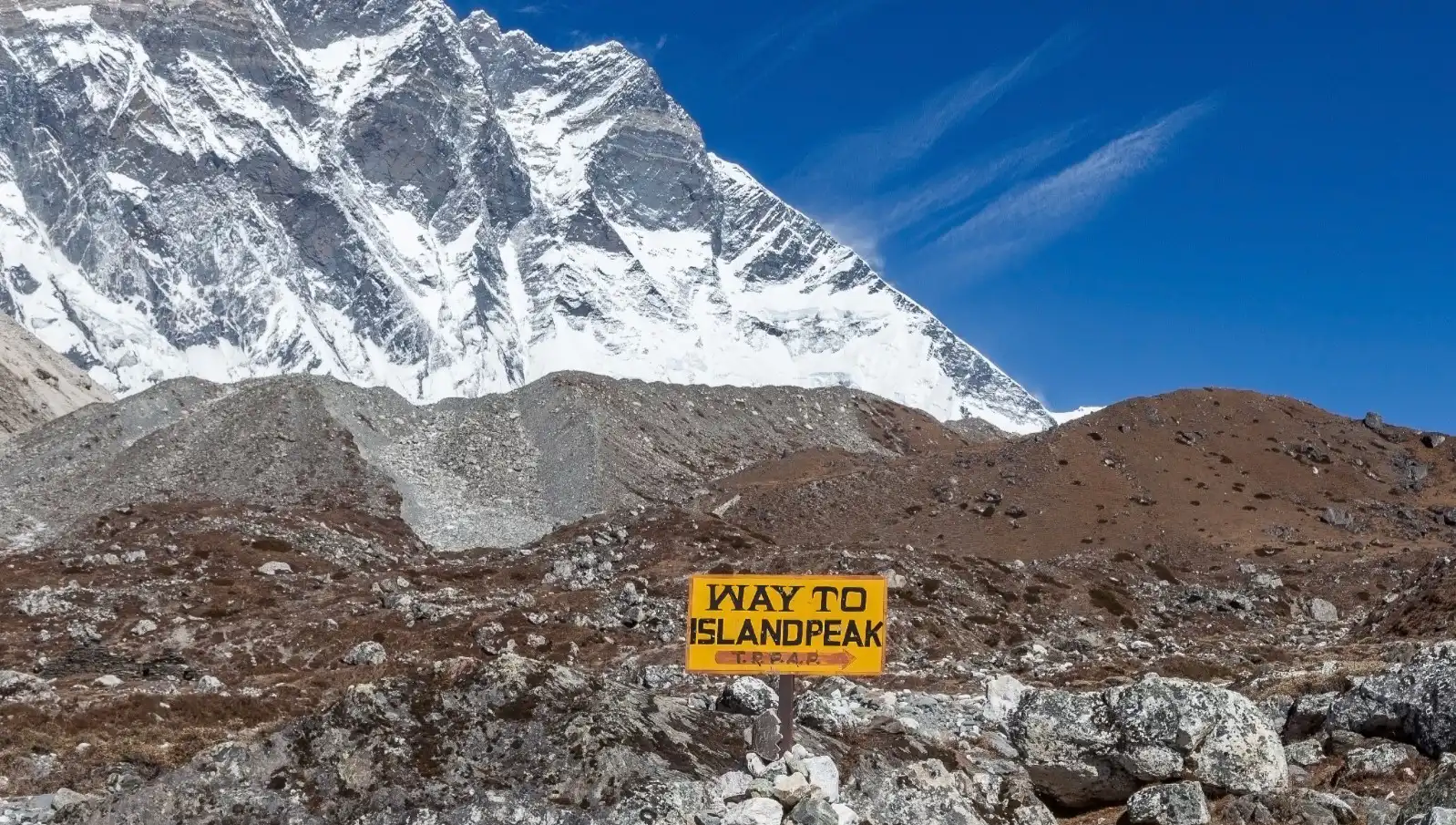 "Way to Island Peak" set against a rugged mountainous landscape with snow-covered peaks and a clear blue sky.