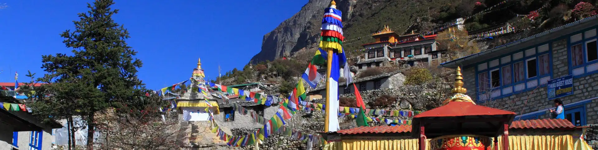 Thamo Village with colorful prayer flags and traditional stone buildings, nestled in the rugged terrain of Sagarmatha National Park, Nepal.