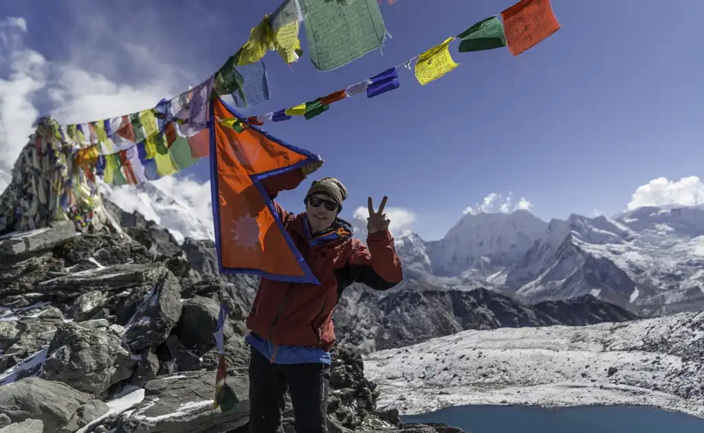 Trekker at Kongma La Pass, 5535m, with prayer flags and mountain views