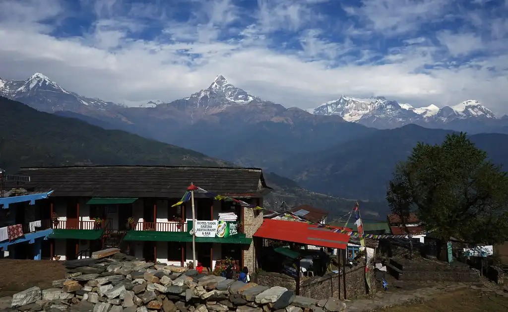 Traditional buildings in Dhampus village, surrounded by lush green hills and framed by the snow-capped peaks of the Annapurna range.