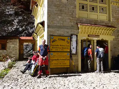 Tourists at the entrance of Sagarmatha National Park with a signboard and ticket office, ready to explore the World Heritage Site.