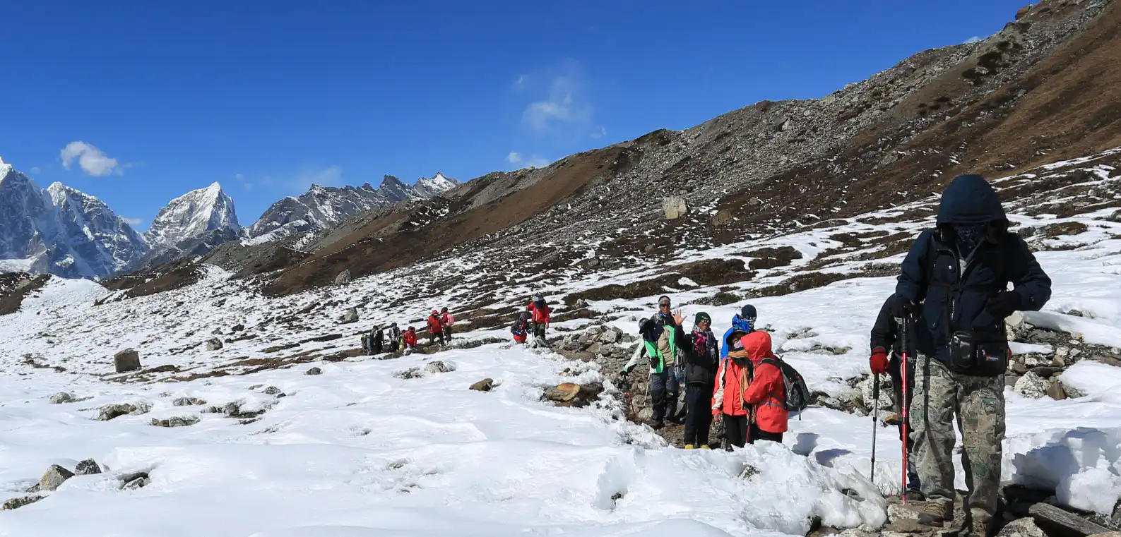 Trekkers making their way across a snow-covered glacier near Everest Base Camp, with the Himalayan peaks towering in the background.