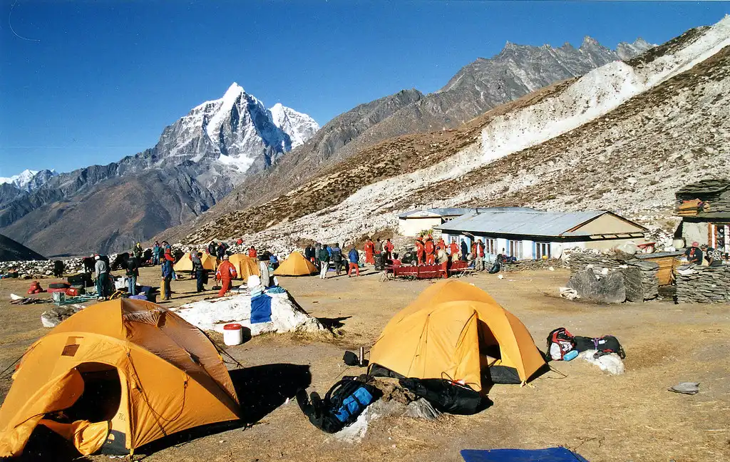 Yellow tents set up in Chhukung under the morning light, surrounded by mountains, as climbers prepare for their final push to Island Peak Base Camp.