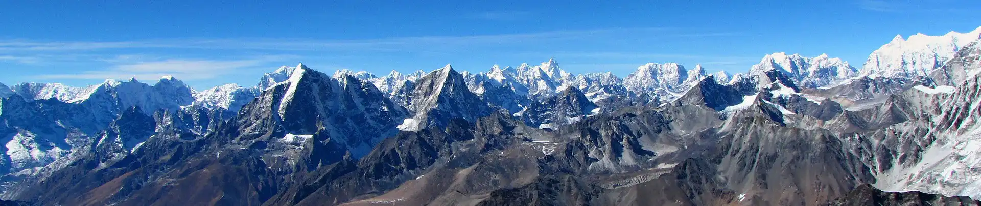 Panoramic view from the summit of Island Peak showing a vast range of the Himalayan mountains under a clear blue sky.